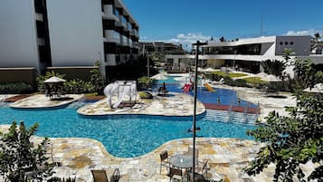 Ein Schwimmbadbereich mit mehreren Pools, Liegestühlen und Sonnenschirmen.