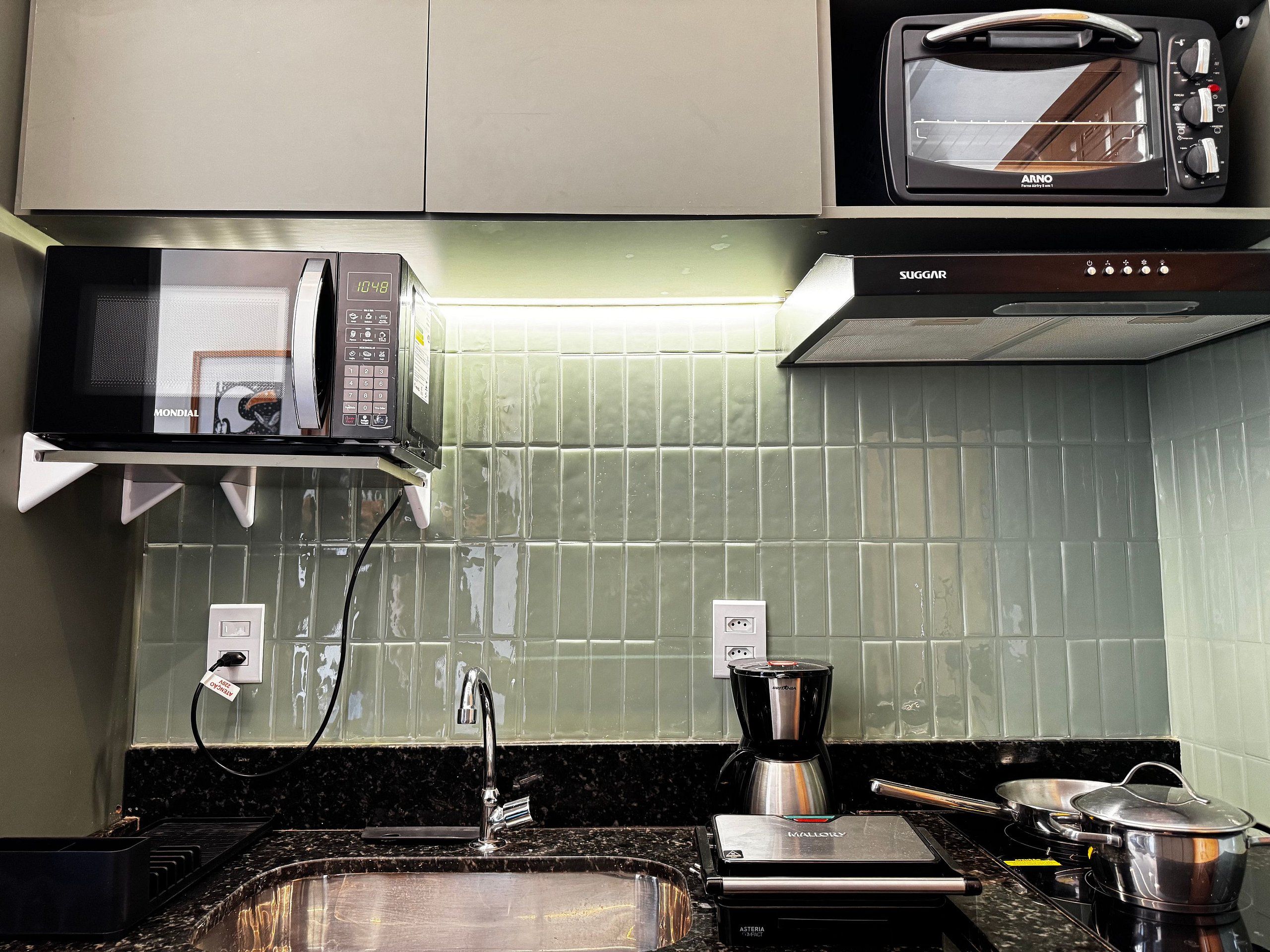 A kitchen with a microwave, toaster, coffee maker, and a sink.