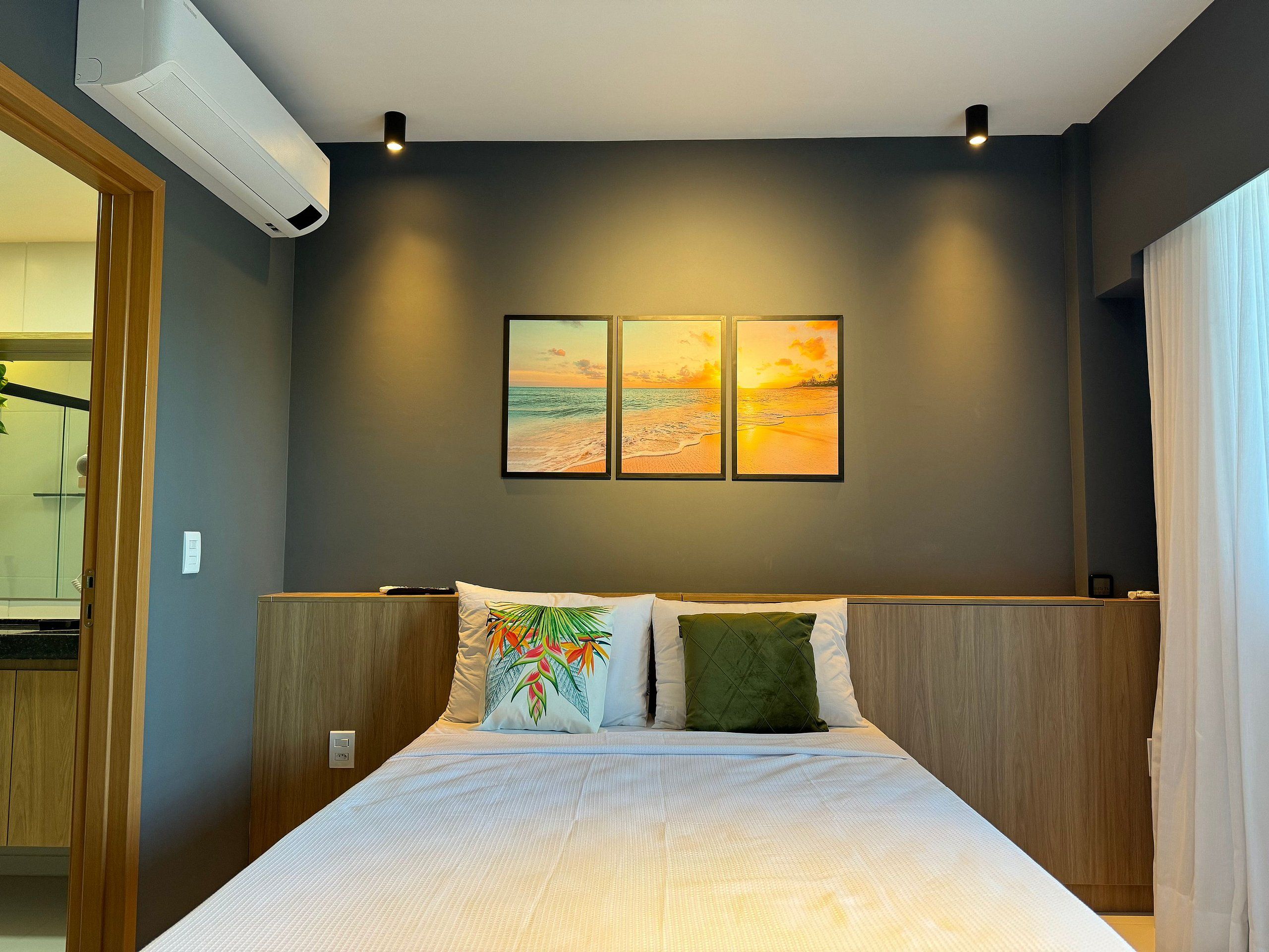 Ein Schlafzimmer mit einem Bett, zwei Kissen, einem Nachttisch und einer Wand-Klimaanlage.