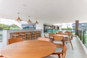 Un comedor moderno con una mesa redonda de madera y sillas, una barra y lámparas colgantes.