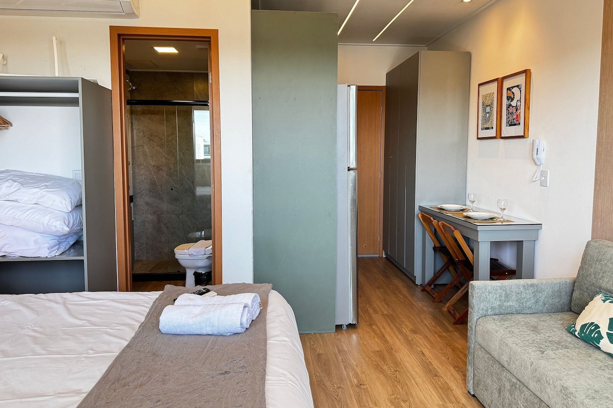 A hotel room with a bed, a desk, a chair, and a bathroom.