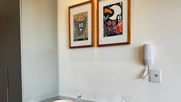 A dining area with a table set for two, a framed artwork above, and a telephone on the wall.