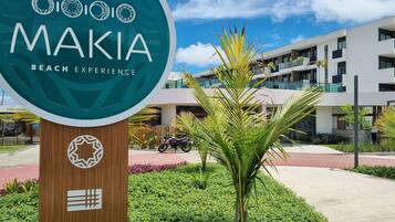 A sign for Makia Beach Experience with a modern building in the background.