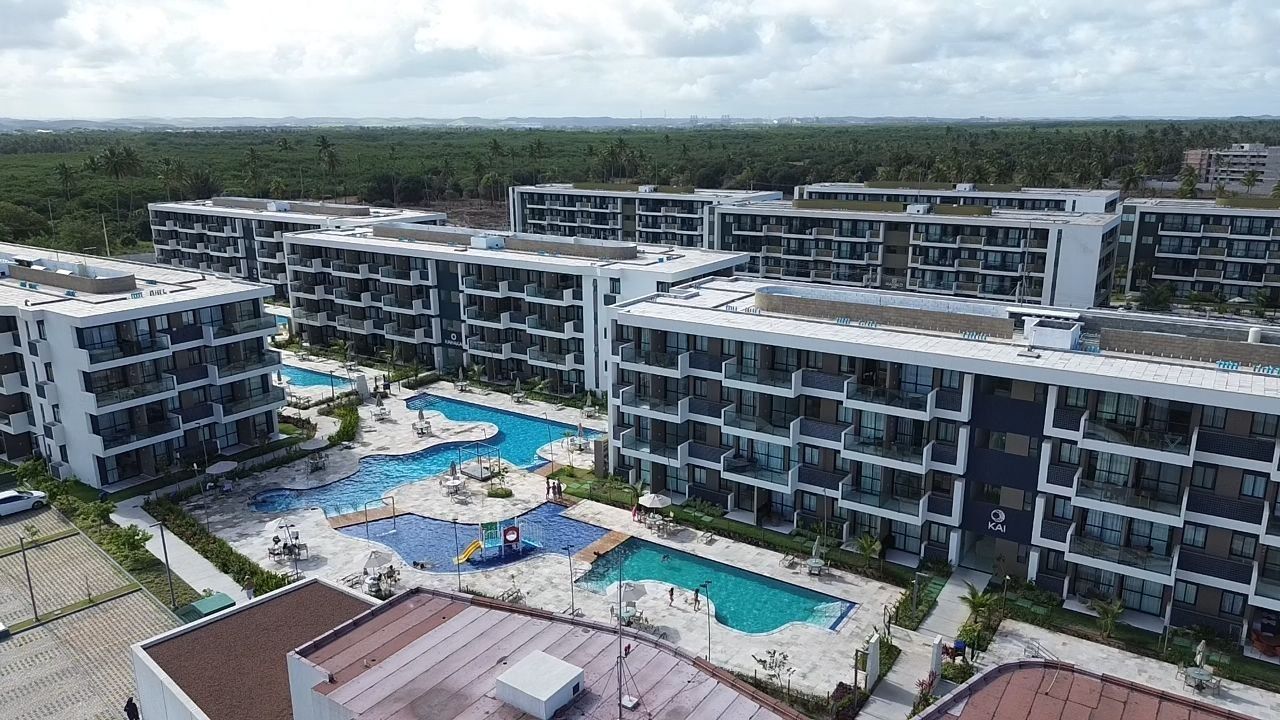 Un moderno complejo hotelero con varias edificaciones, una piscina central y una zona ajardinada.