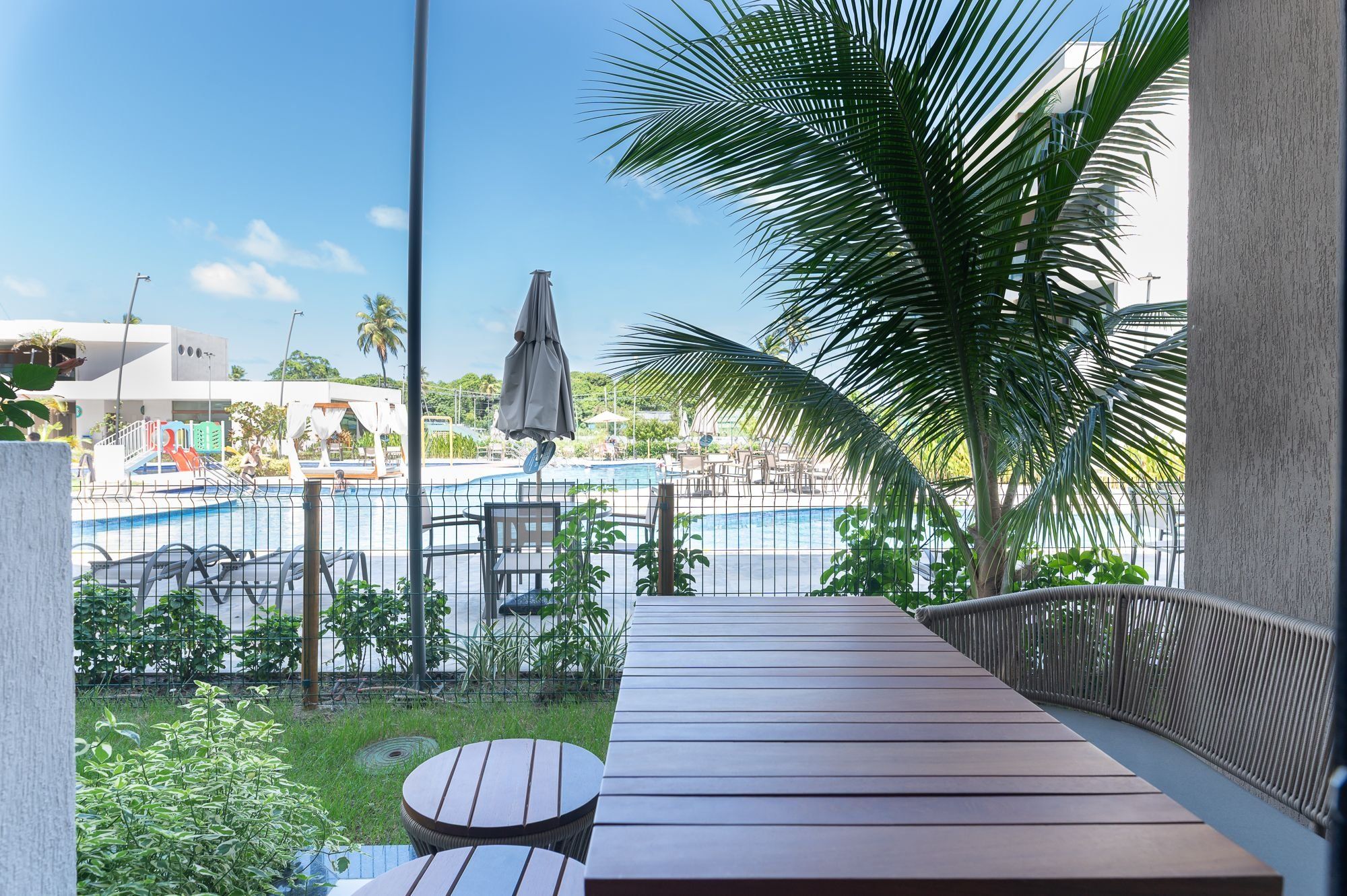 Terraza de madera con vista a una piscina y zona de descanso.