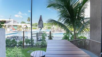 Terraza de madera con vista a una piscina y zona de descanso.