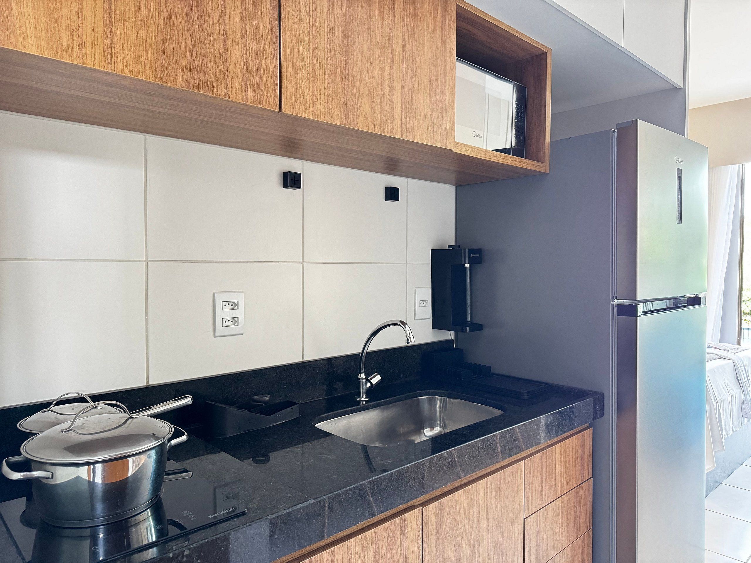 Una cocina moderna con gabinetes de madera, un lavamanos de acero inoxidable y un microondas integrado.