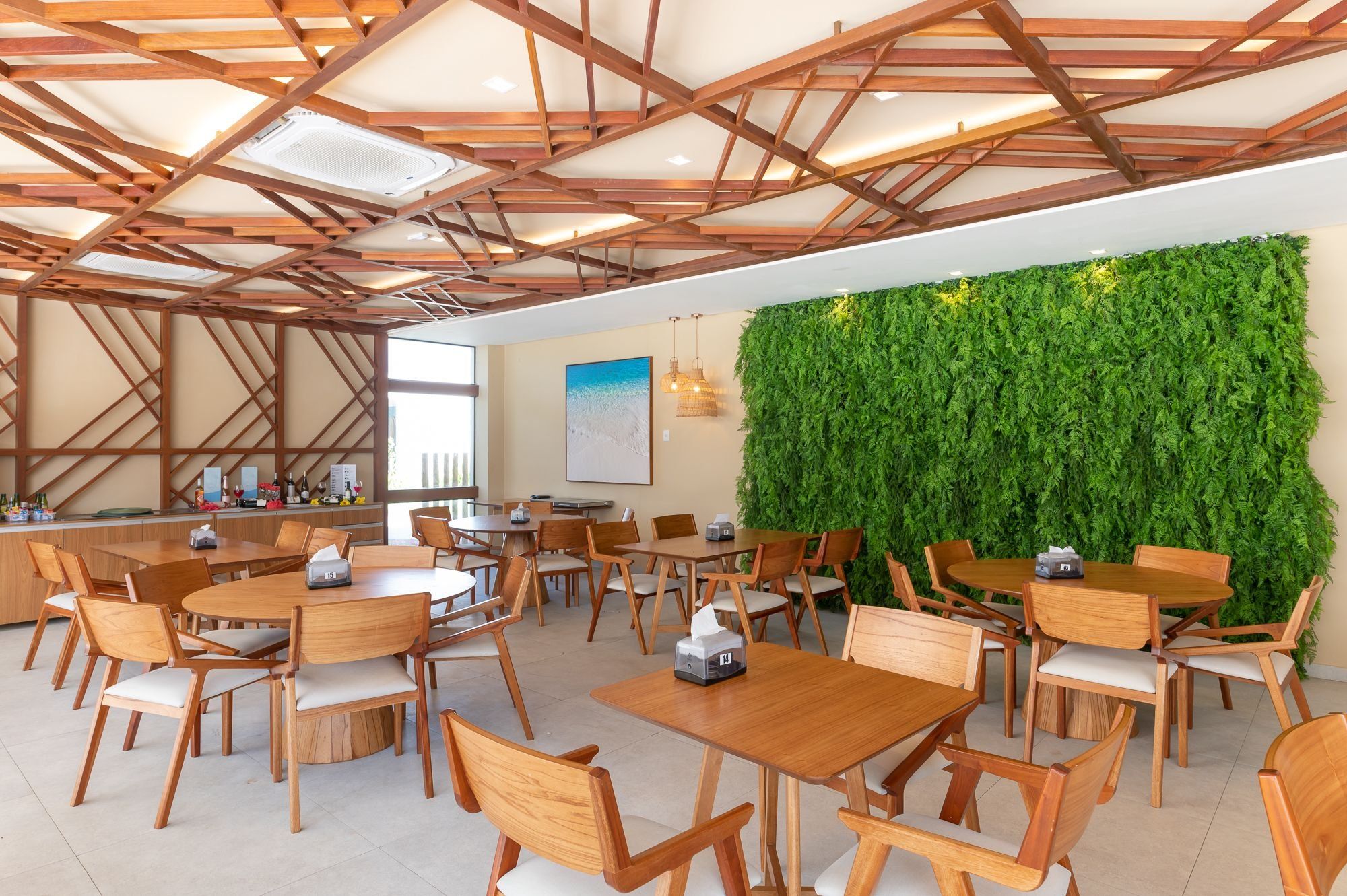 Un espace de restauration intérieur moderne, avec des tables et des chaises en bois, un mur végétal et un plafond orné de poutres en bois.