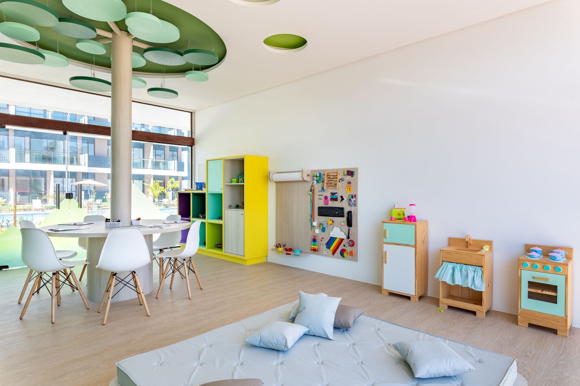 Ein modernes Kinderzimmer mit Schreibtisch, Stühlen, einem Bett und einem Spielbereich.
