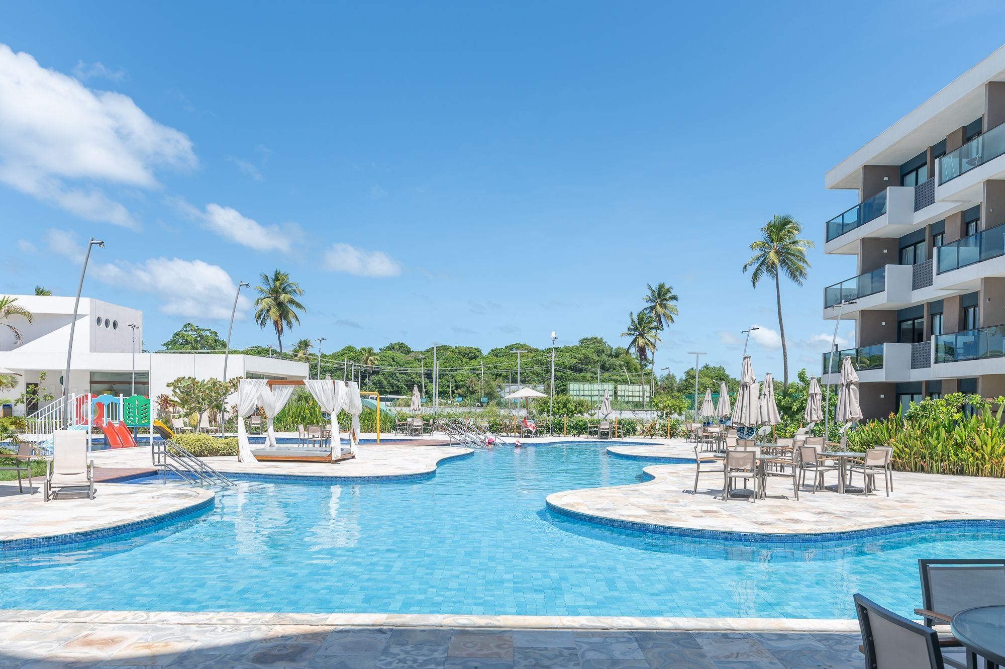 A pool area with multiple swimming pools, lounge chairs, and umbrellas.