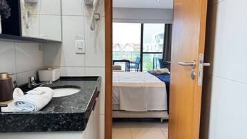 A hotel room with a bathroom, a bed, a window, and a view of the outside.
