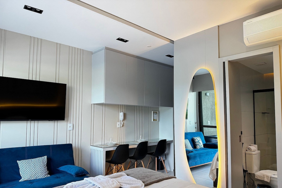 A modern hotel room with a bed, a desk, a TV, and a bathroom.