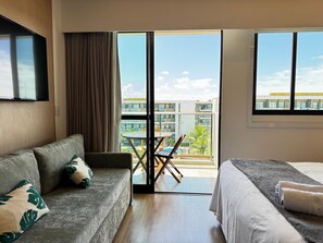 Quarto de hotel com sofá, cama, mesa de jantar e vista para o exterior.