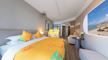 Habitación de hotel con cama, escritorio, silla, mesita de noche, lámpara, un cuadro de playa y una ventana.