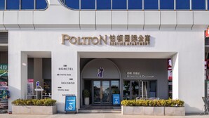 Um edifício com uma placa indicando 'Polton Service Apartment' e 'HOMETEL & DELISHOP', mostrando um hotel e uma loja.