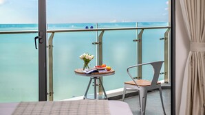 Uma varanda com uma mesa, uma cadeira e vista para o mar.