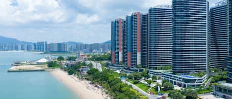 A coastal cityscape with high-rise buildings, a beach, and a clear sky.