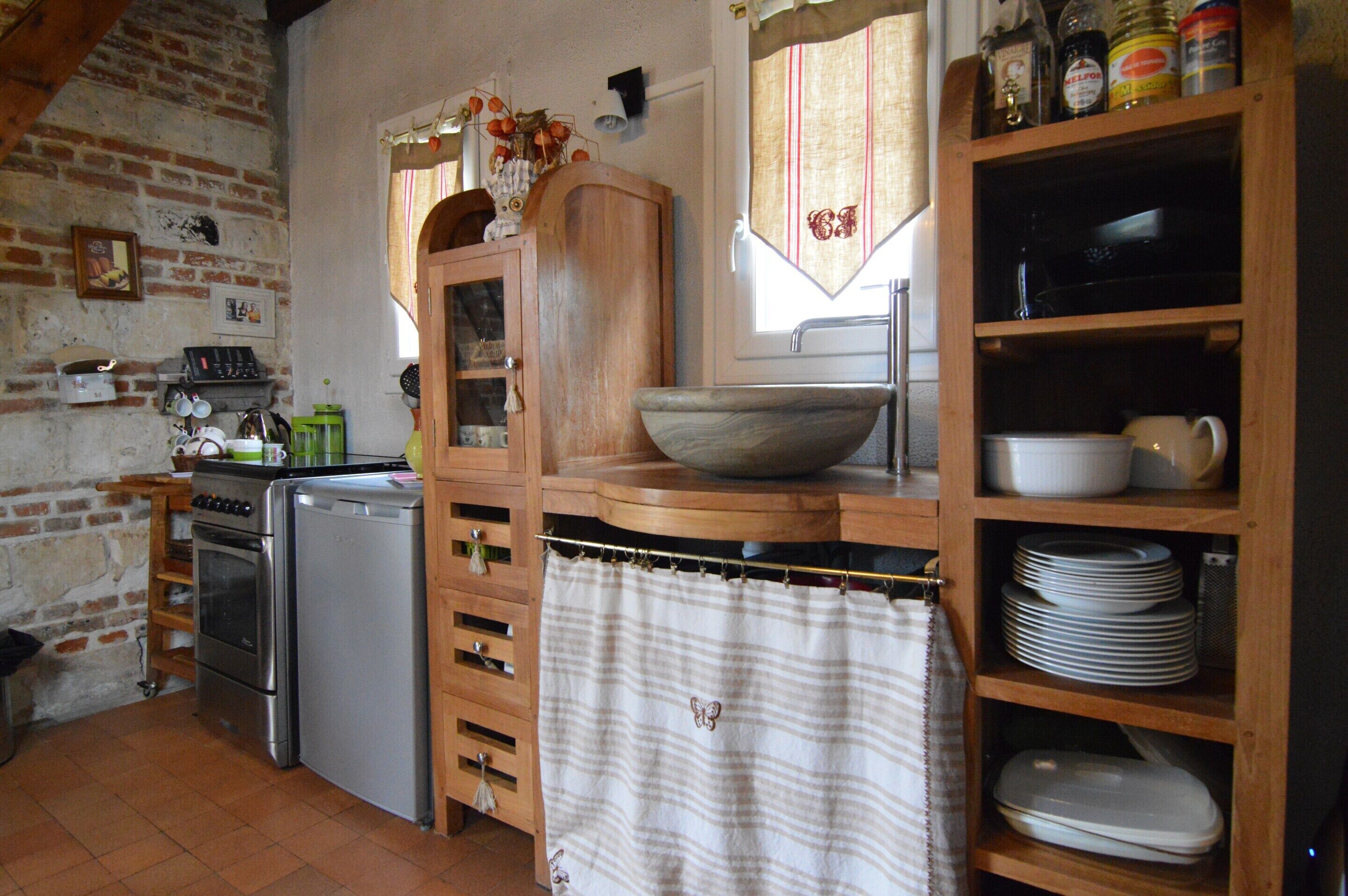 A kitchen with a brick wall, wooden cabinets, a sink, and a stove.