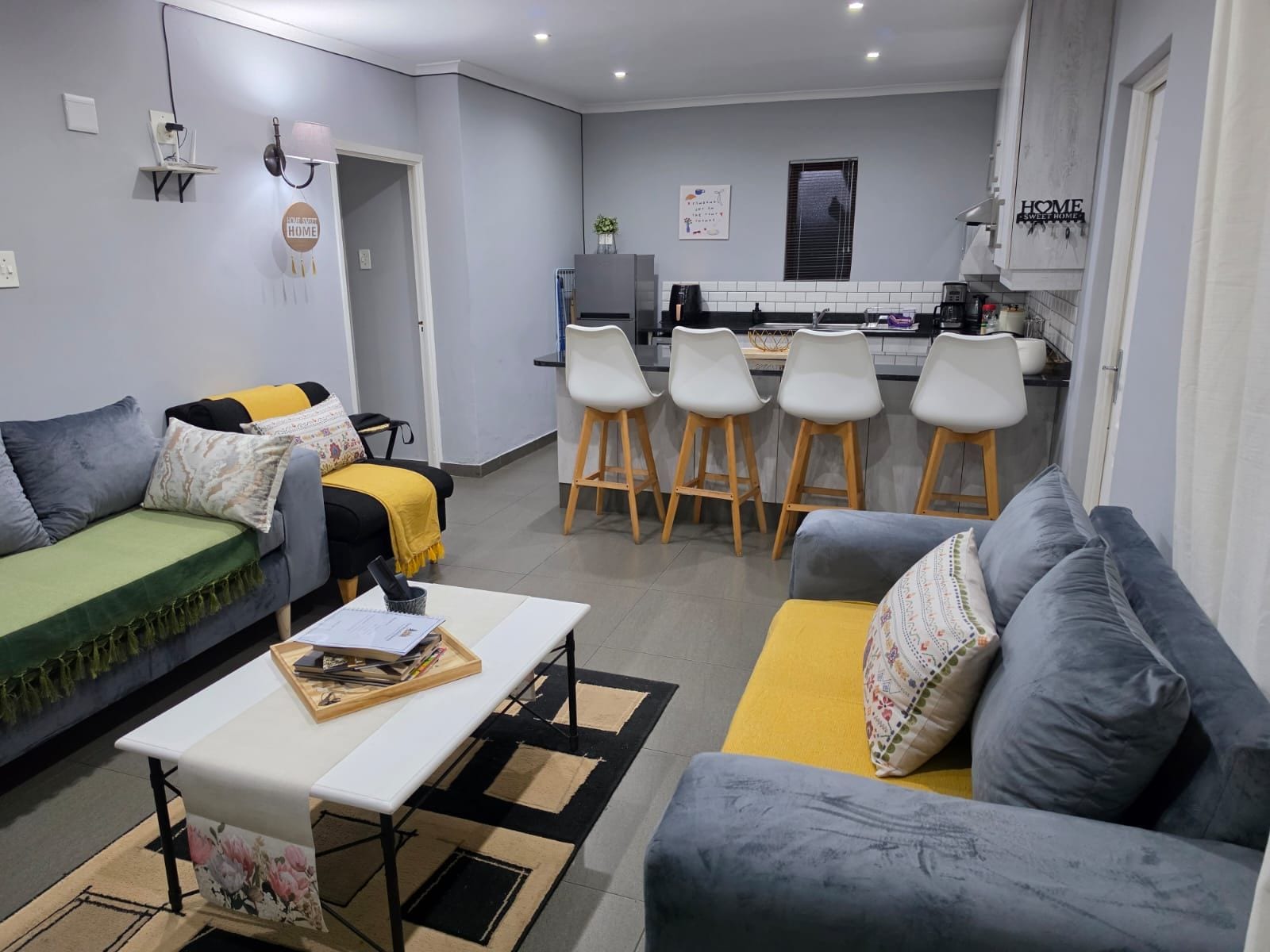 A modern living room with a sofa, a dining table, and a kitchen area in the background.