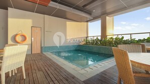 Ett poolområde på taket med möbler i rotting, en livboj och en dörr med texten ”Kozva”.