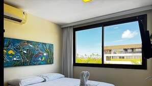 Ein Hotelzimmer mit einem Bett, einem Gemälde, einem Fenster mit Aussicht und einer Klimaanlage.