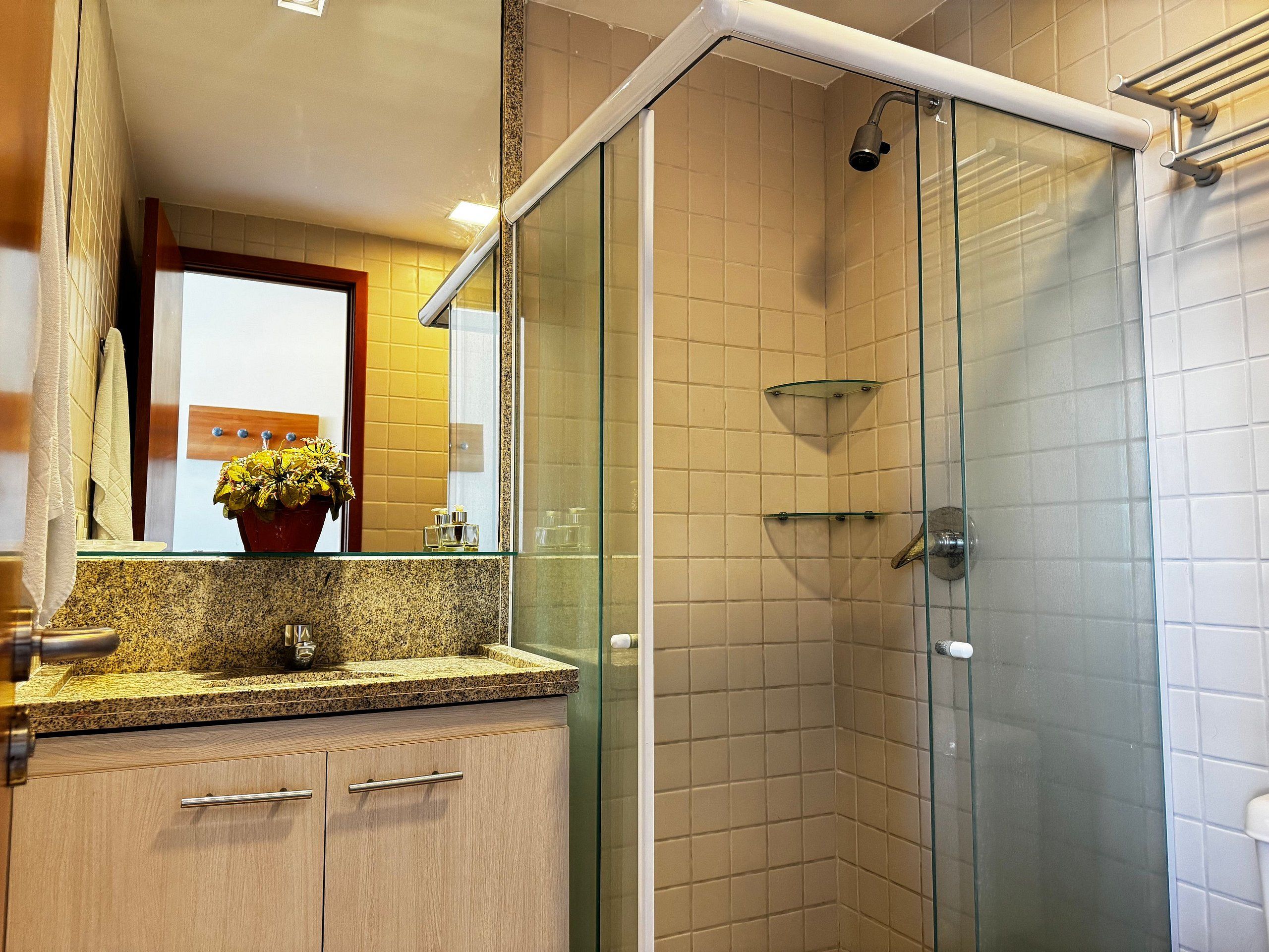 Une salle de bain moderne avec une douche à parois de verre, un comptoir en granit et un meuble en bois.
