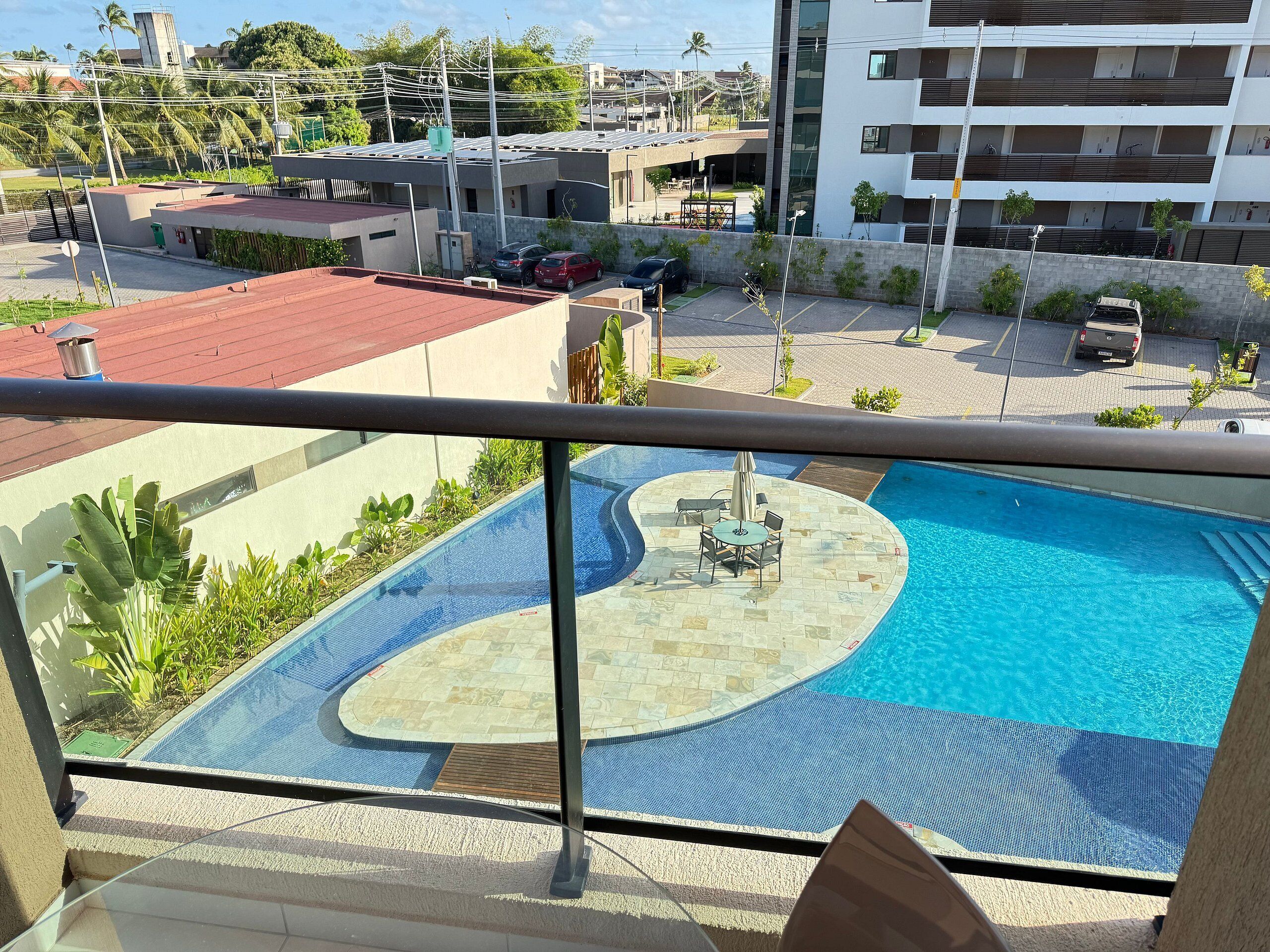 Una piscina con zona de solárium, rodeada por un balcón con barandilla.