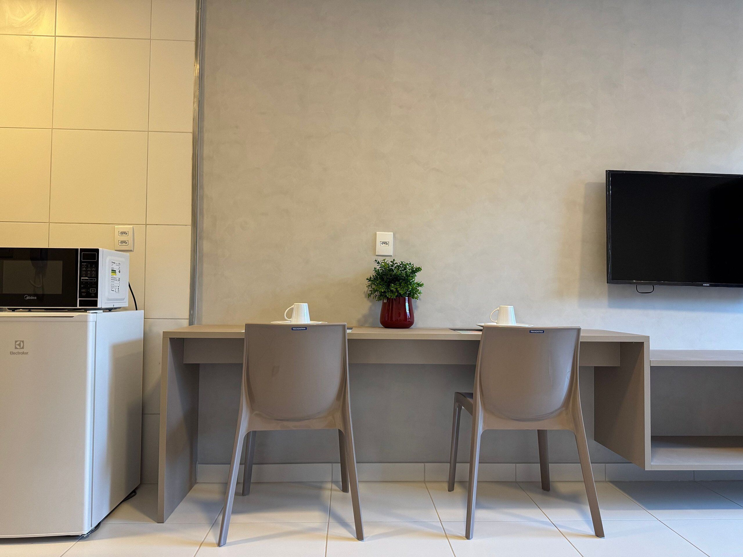 Una kitchenette moderna con microondas, refrigerador y un televisor de pantalla plana montado en la pared.