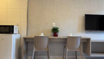 Una kitchenette moderna con microondas, refrigerador y un televisor de pantalla plana montado en la pared.
