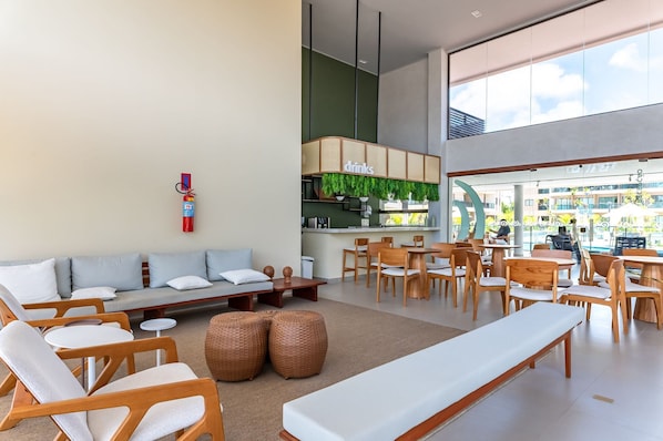 A modern lounge area with seating arrangements, a bar, and a view of the outdoors.