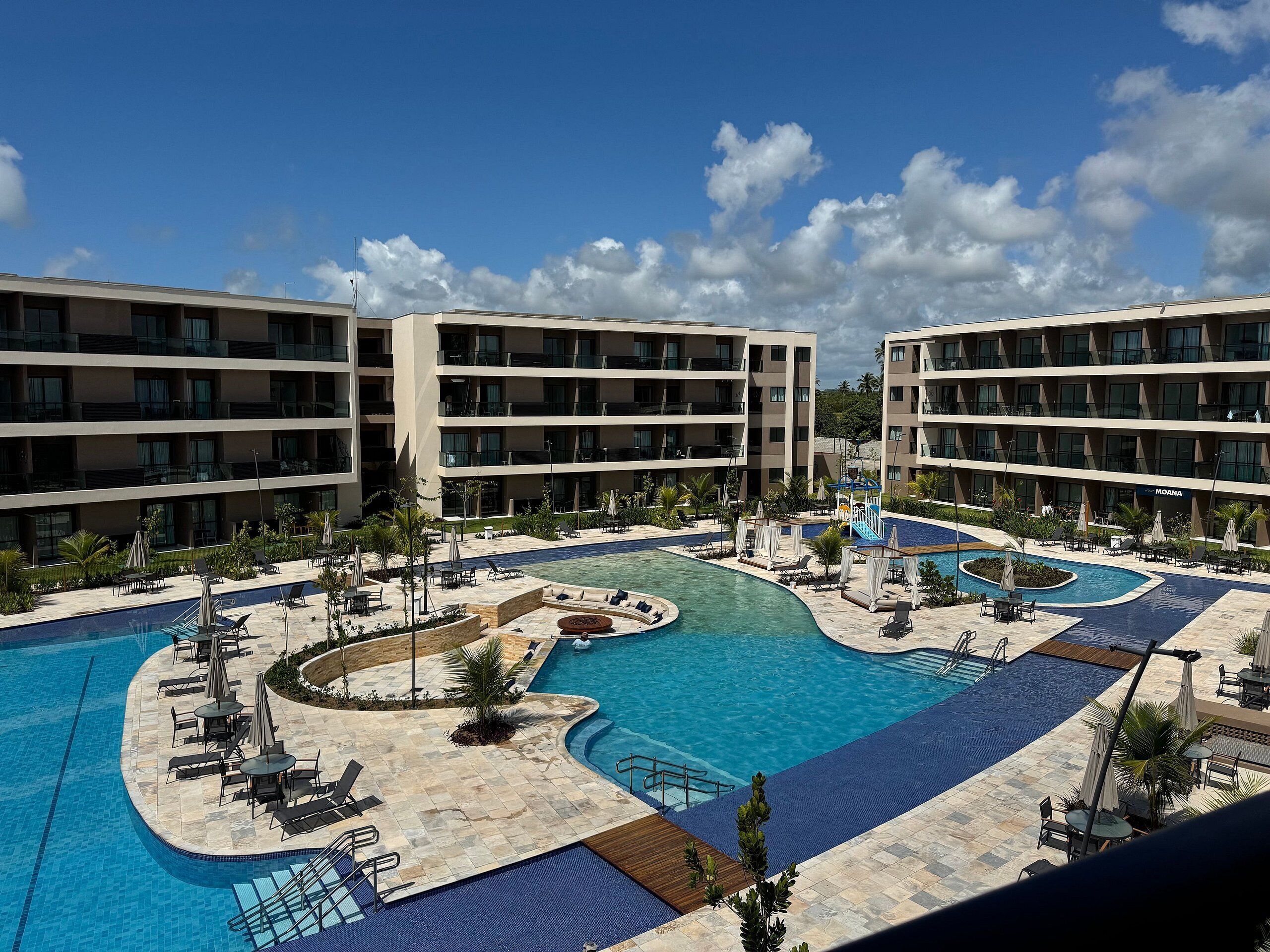 Un hotel con varias plantas, una piscina central y zonas de estar al aire libre.