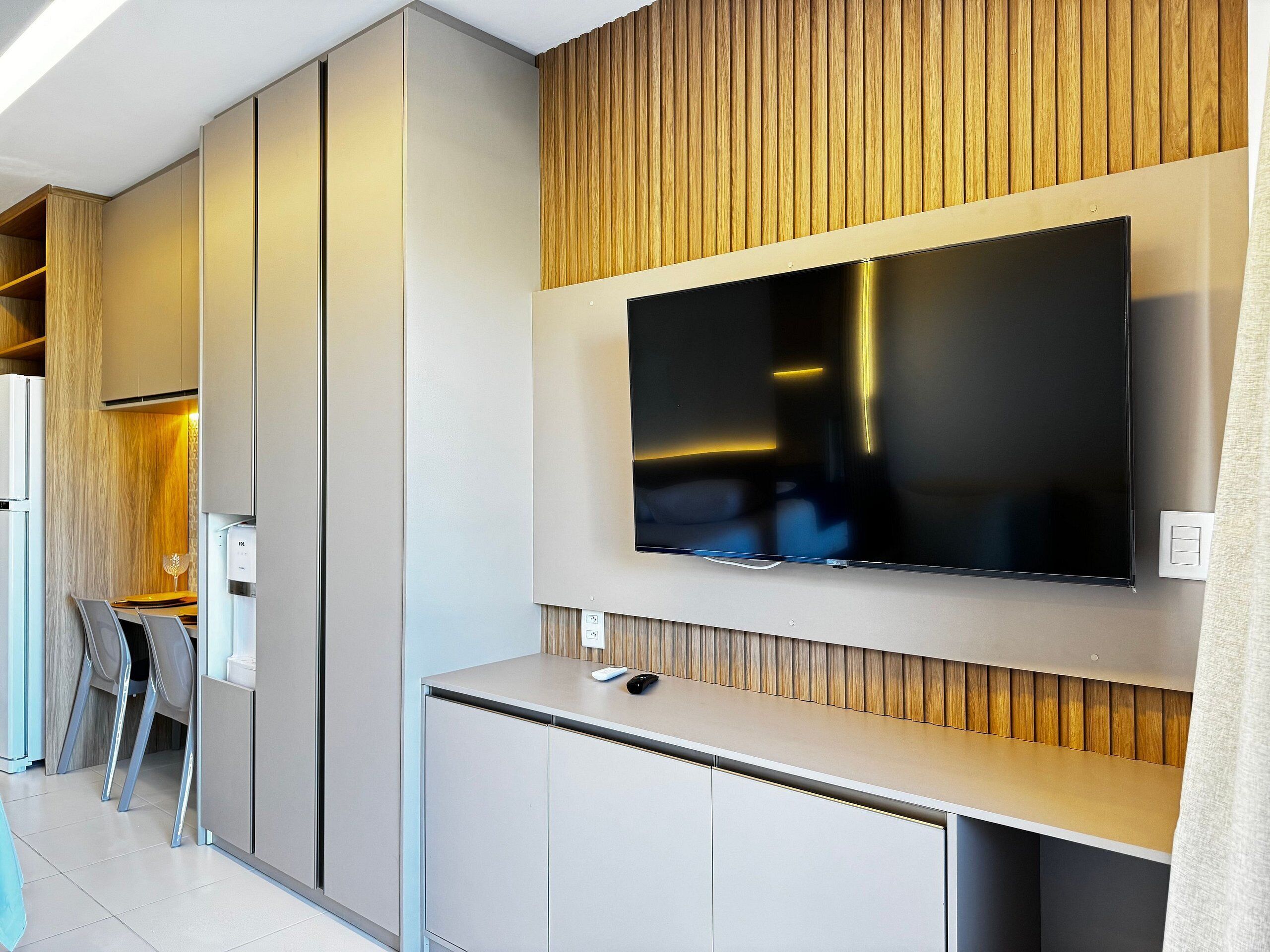 Una cocina moderna con televisión integrada, armarios y una pared decorativa de madera.