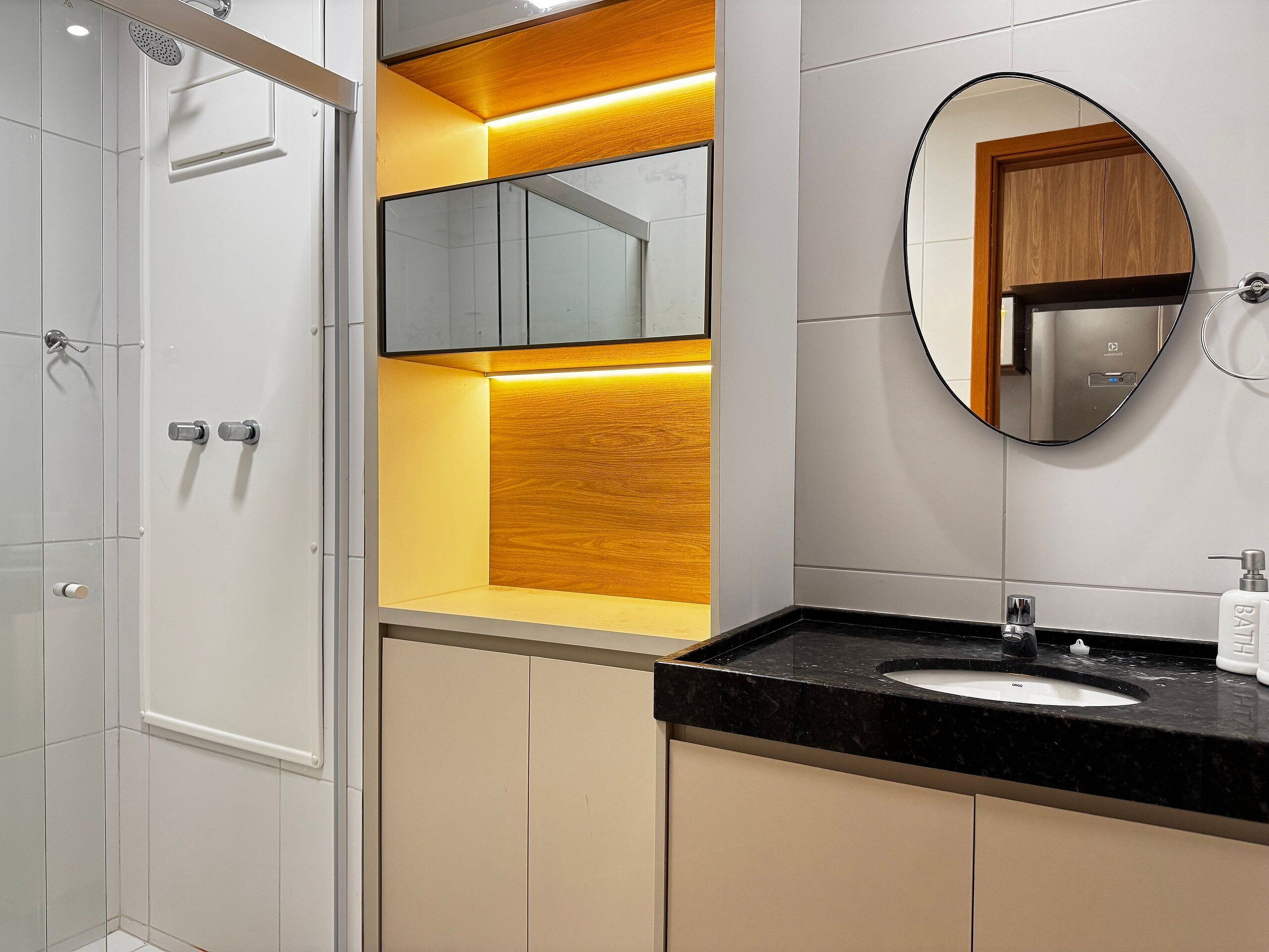 A modern bathroom with a black sink, a mirror, and a shower enclosure.