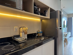 Eine moderne Küche mit integriertem Backofen, einem Edelstahlkühlschrank und einer Arbeitsplatte mit Messerhalter.