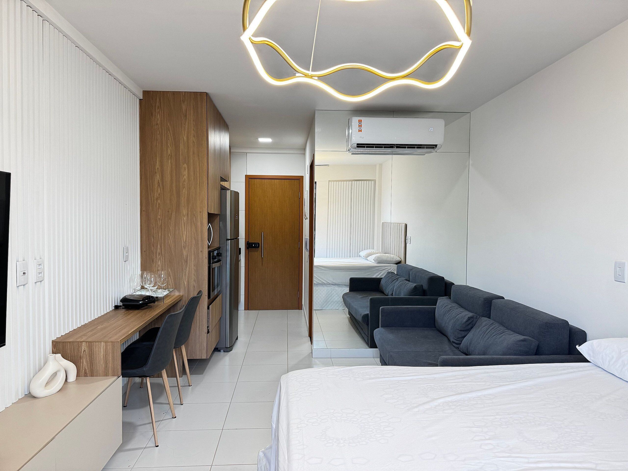 Una habitación de hotel moderna con cama, sofá, escritorio y kitchenette.