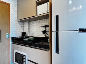 A kitchen with a built-in oven, a refrigerator, and a coffee maker.