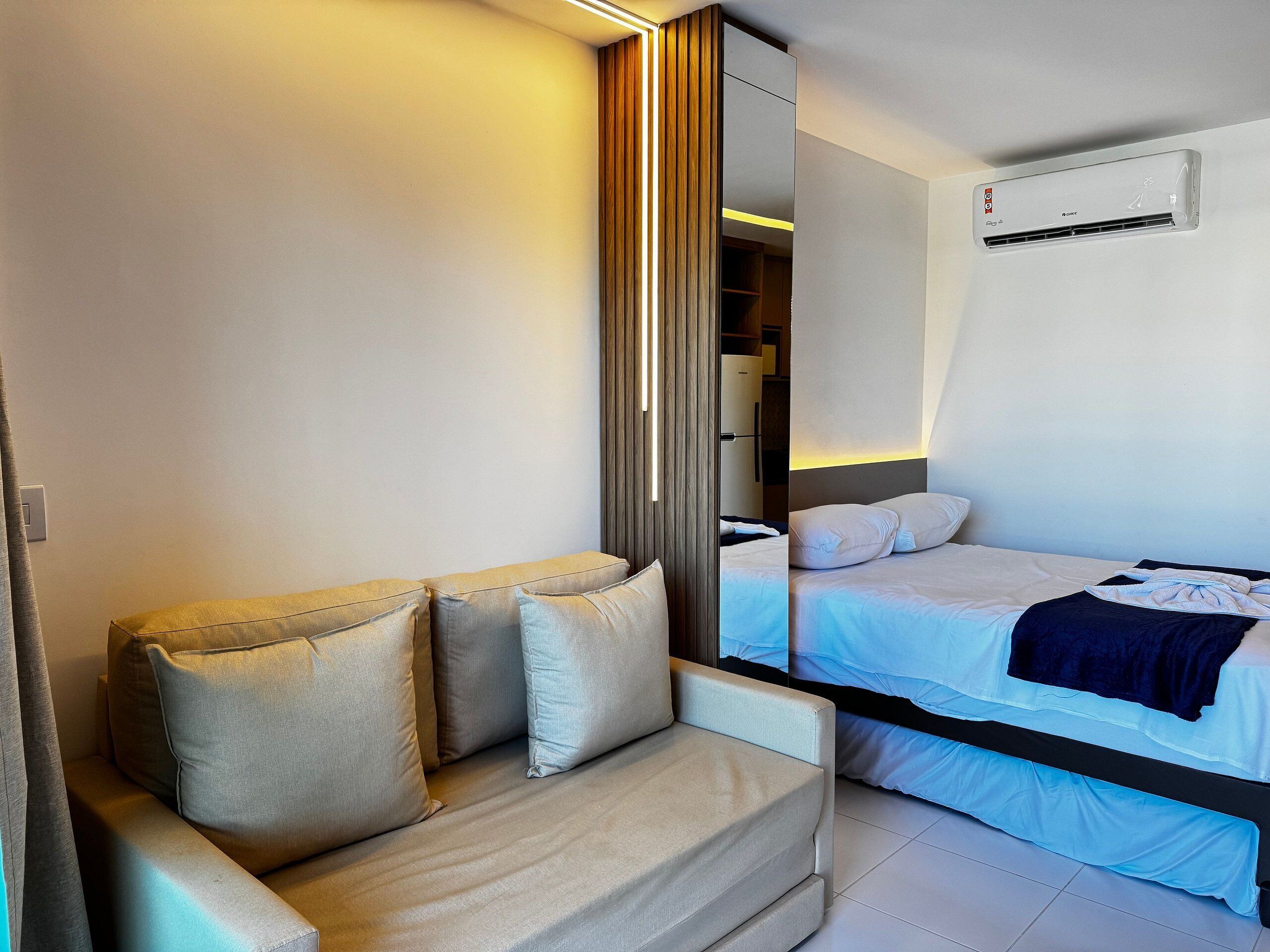 A modern hotel room with a sofa, a bed, and a wardrobe.