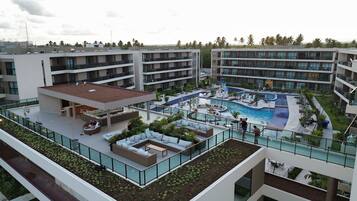 Un hotel de varios pisos con piscina en la azotea, zona de estar al aire libre y jardín ajardinado.
