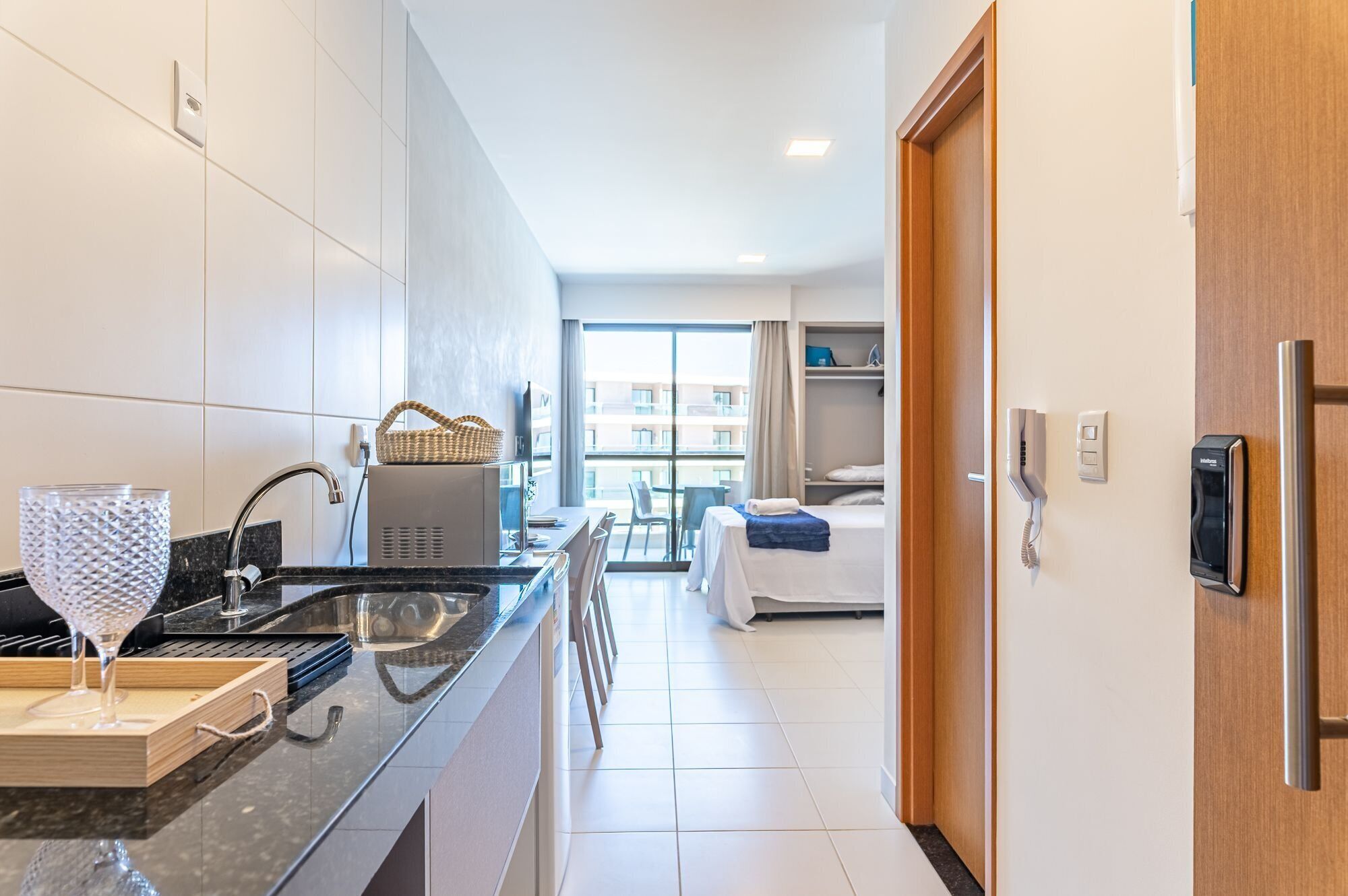Quarto de hotel moderno com cozinha, mesa de jantar e uma cama.