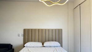 Een hotelkamer met een bed, hoofdeinde en een moderne lamp.