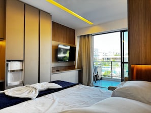 A hotel room with a bed, a TV, a water dispenser, and a view of an outdoor pool.