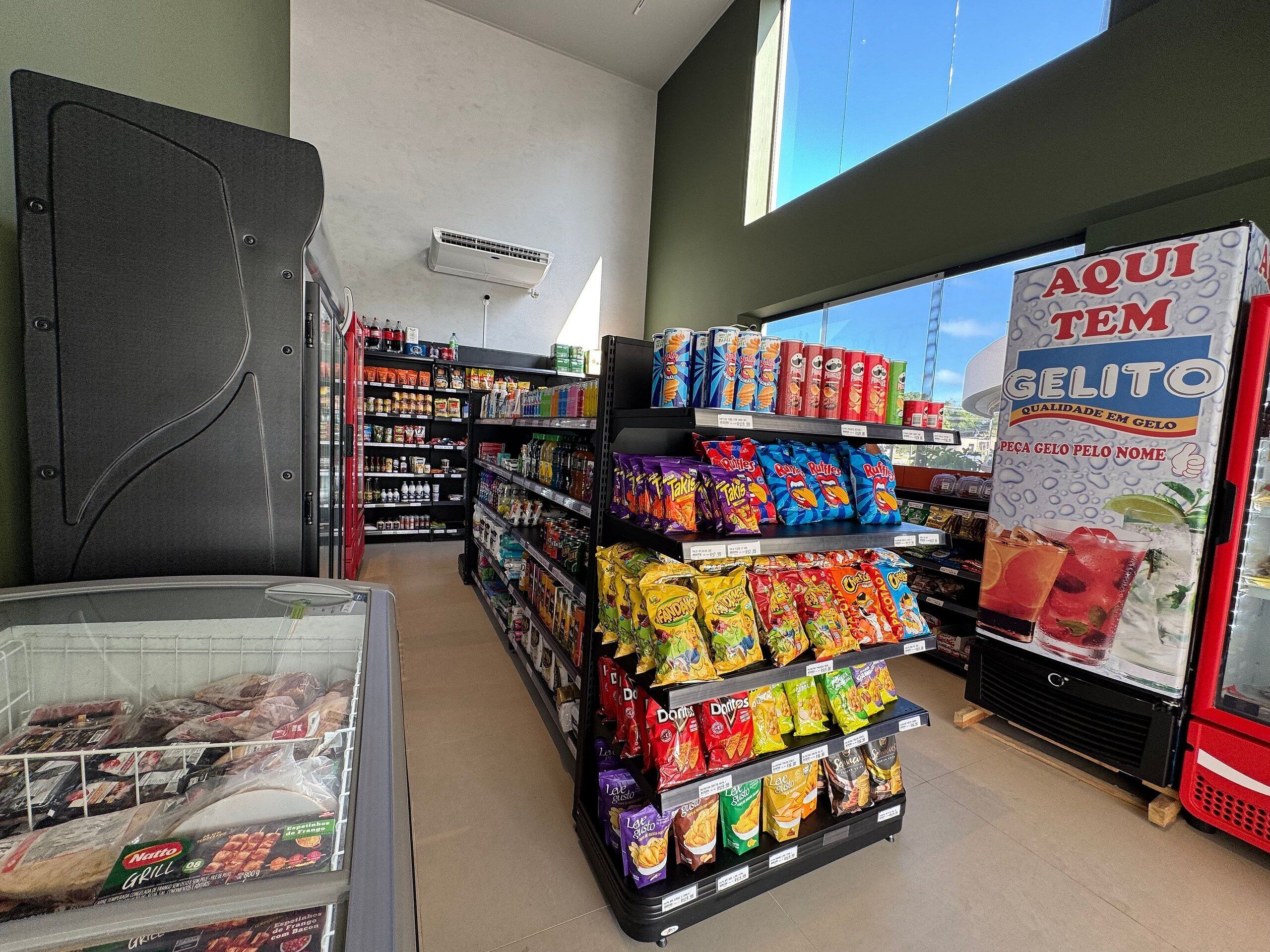 A grocery store interior with shelves stocked with snacks, a freezer section, and a freezer with ice cream.