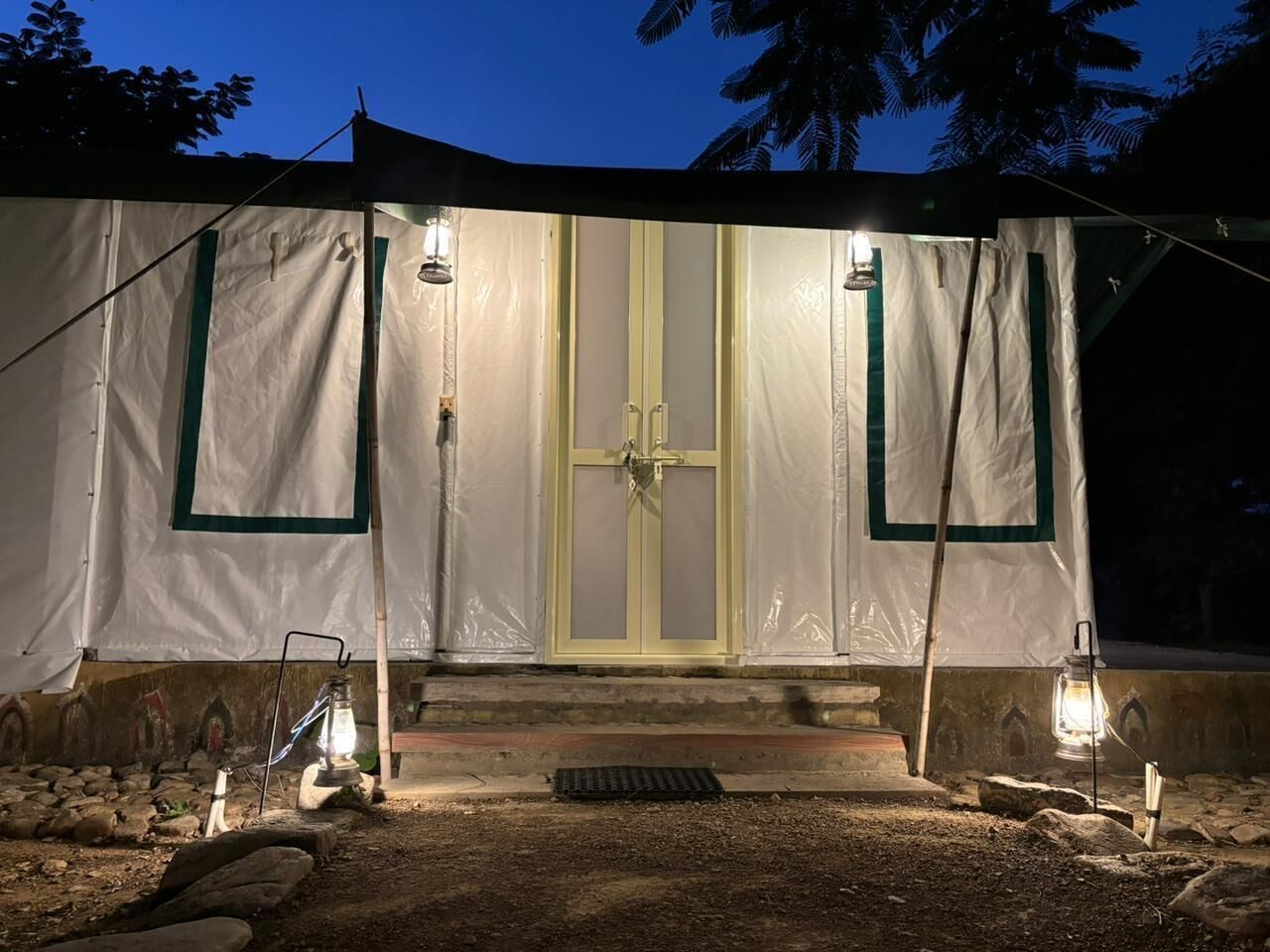 A tent with a central door, two lanterns, and a stone pathway leading to the entrance.