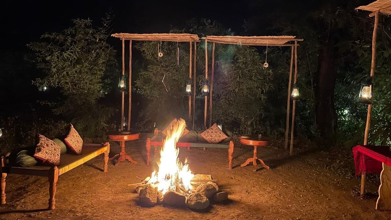 Un espacio al aire libre con un brasero, mesas de madera y bancos.