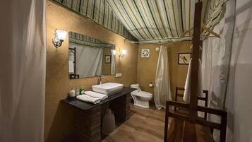 A bathroom with a striped ceiling, a sink, a toilet, and a shower curtain.