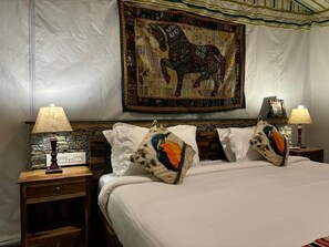 Ein Schlafzimmer mit einem Bett, zwei Nachttischen, zwei Lampen und einem Wandteppich.