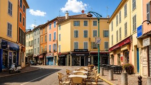A street with cafes and shops, outdoor seating, and a clear sky. - Apartment Le Cèdre  by Sur la mer (Le Muy)