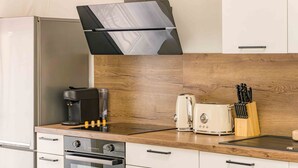 A modern kitchen with a built-in oven, a coffee machine, a toaster, and a knife block on the countertop. - Apartment Le Cèdre  by Sur la mer (Le Muy)