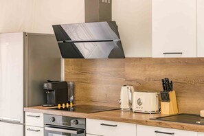 Eine moderne Küche mit integriertem Backofen, einer Kaffeemaschine, einem Toaster und einem Messerblock auf der Arbeitsfläche.