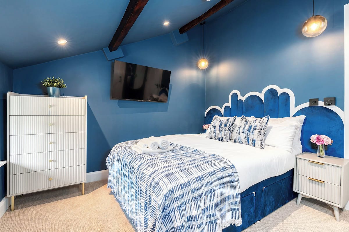 A bedroom with a bed, a dresser, a TV, and a nightstand.
